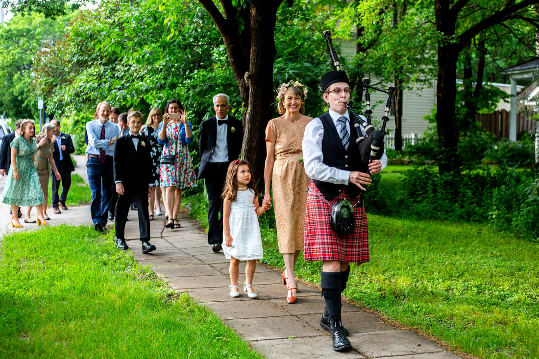 Wedding guests being led by bagpiper to the wedding reception venue, Minneapolis, MN.